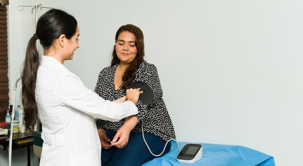 Female doctor checks female patient's blood pressure 