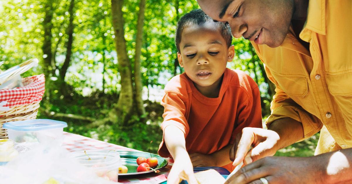 A father and son hosting a picnic outside. 