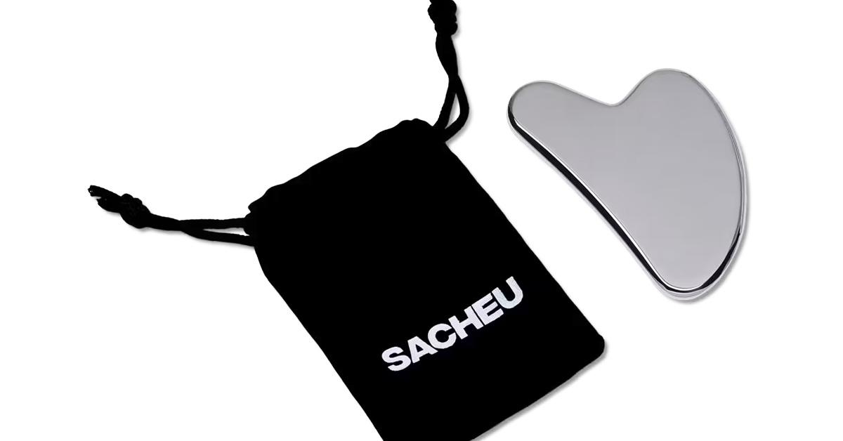 A stainless steel gua sha and a black drawstring satchel