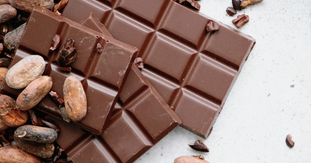 Cocoa beans sit on top of chocolate squares and broken bits of chocolate shavings