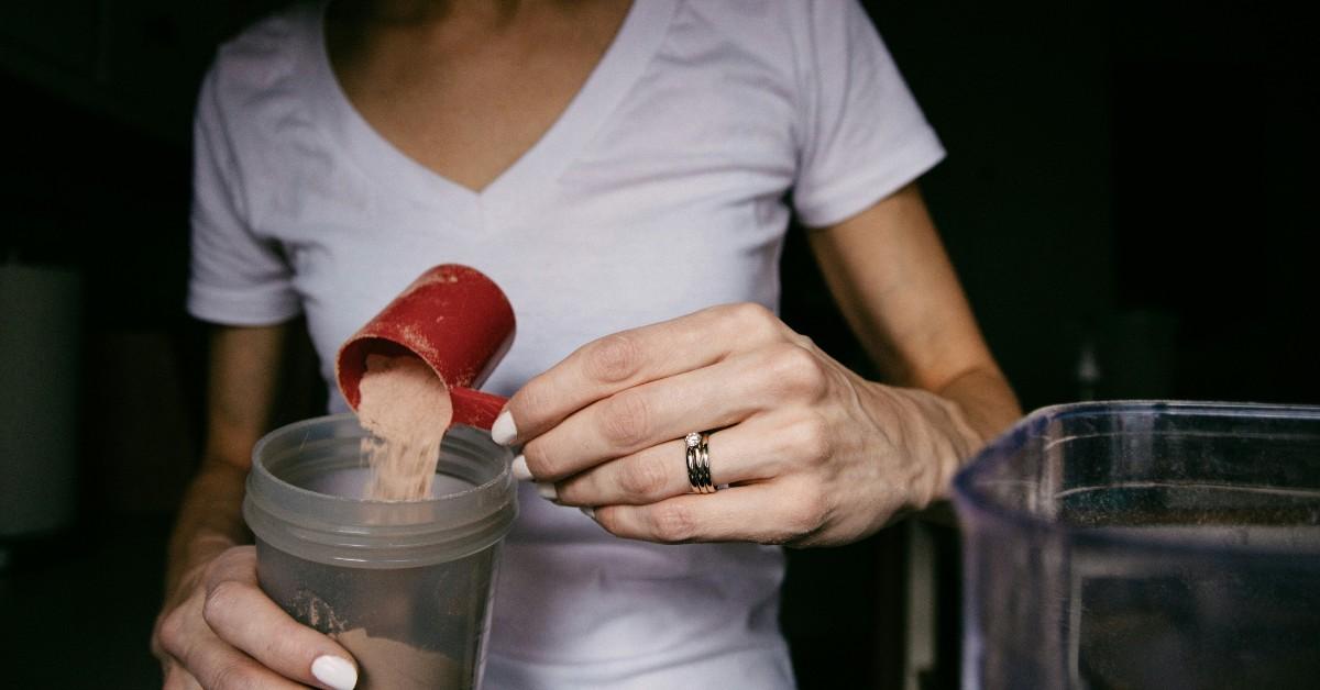 A woman dumps protein powder into her drink