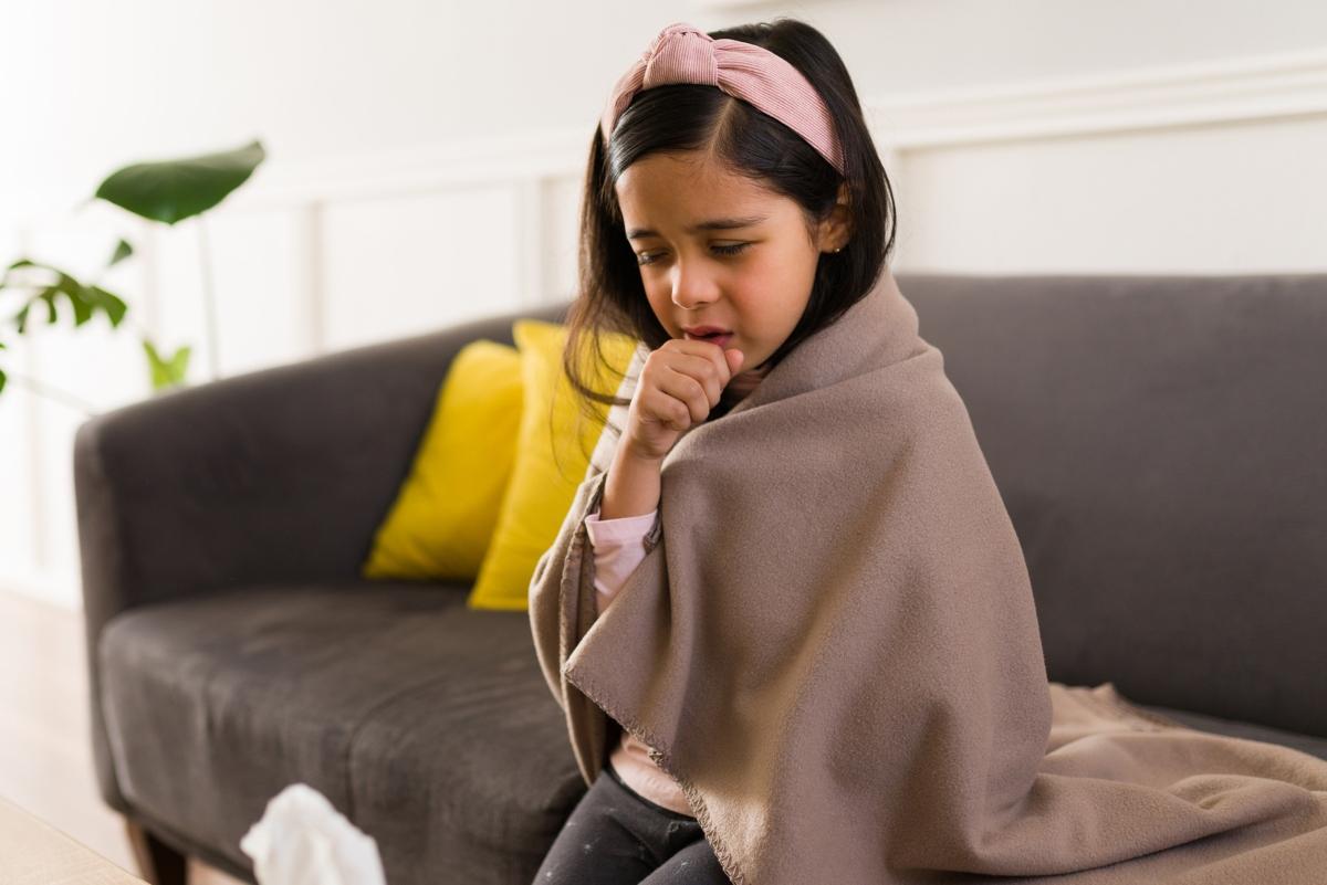 Sick girl coughing and wrapped in a blanket