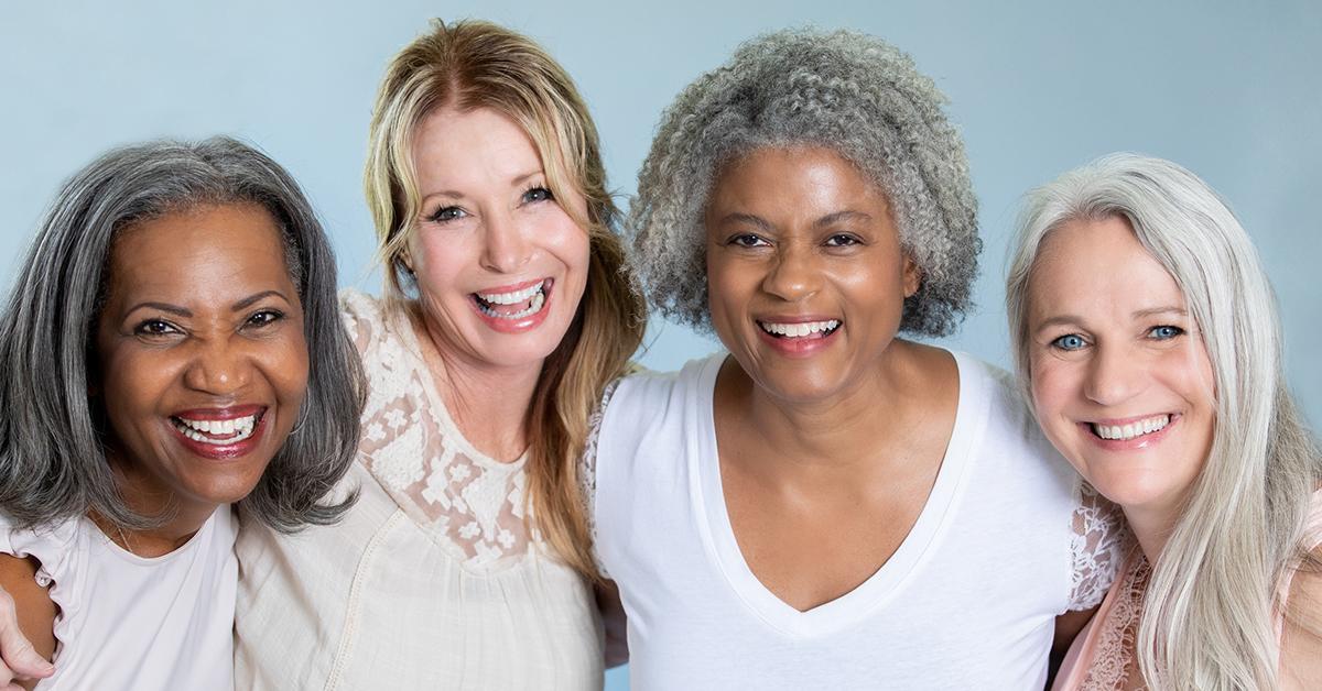 Four women smiling with grey hair.