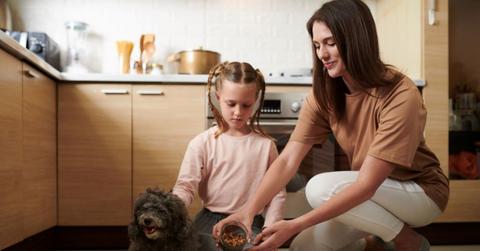 Woman and daughter feeding dog