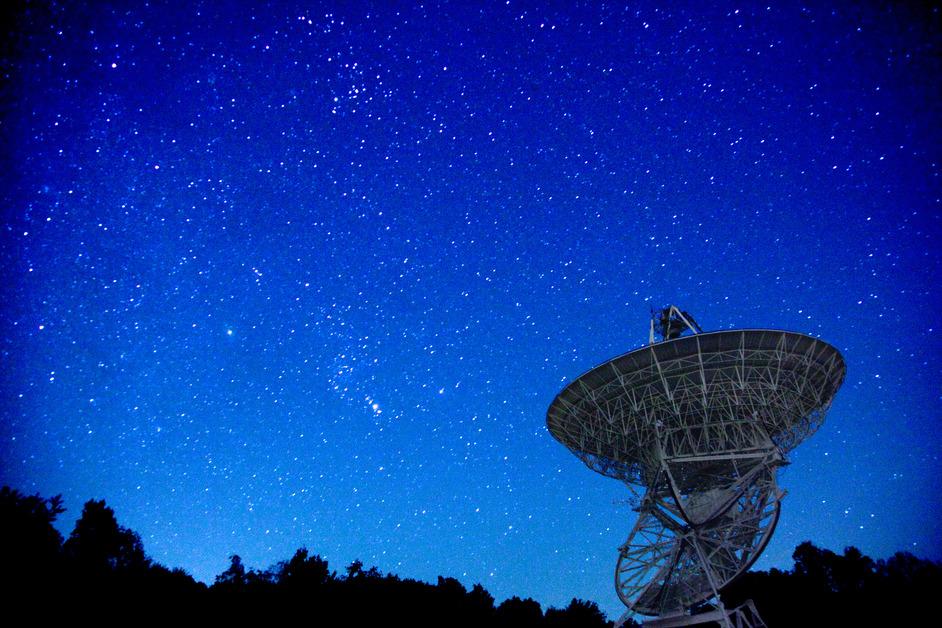 Satellite pointed upwards towards a starry night sky.