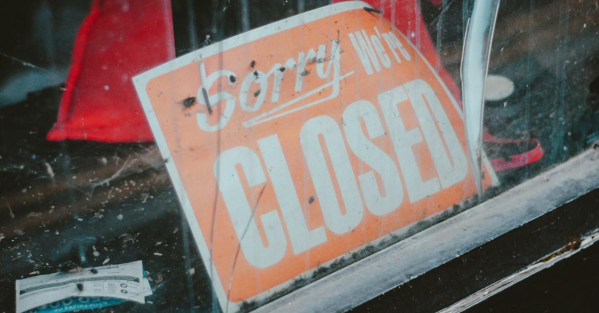A closed sign hangs in an empty storefront