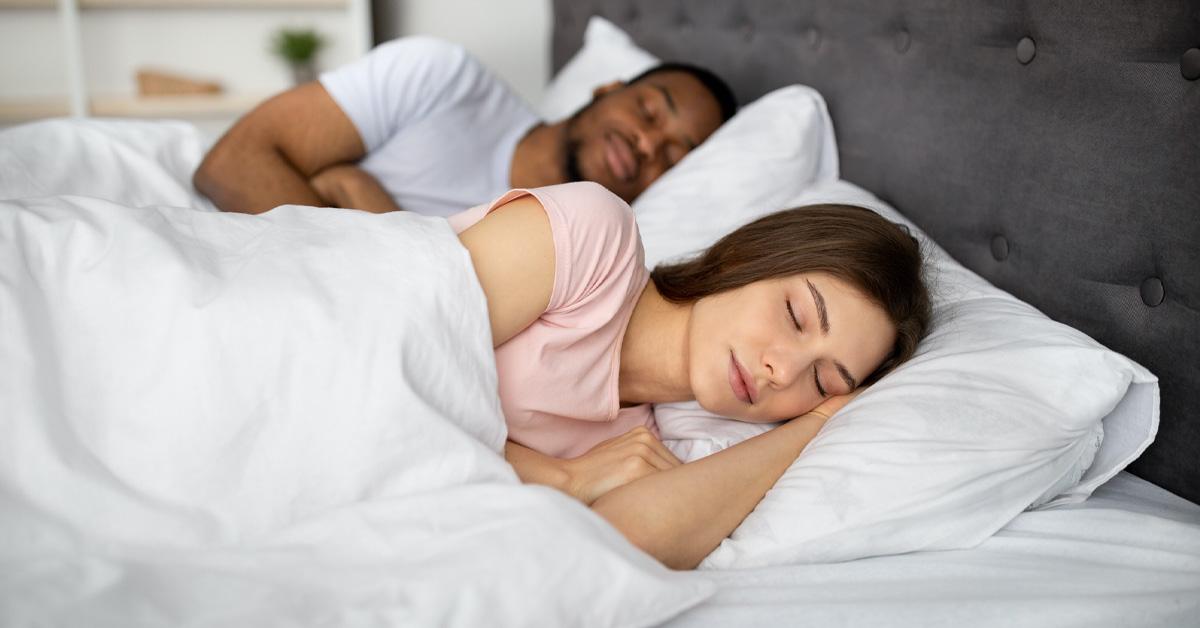 couple sleeping in bed on white sheets