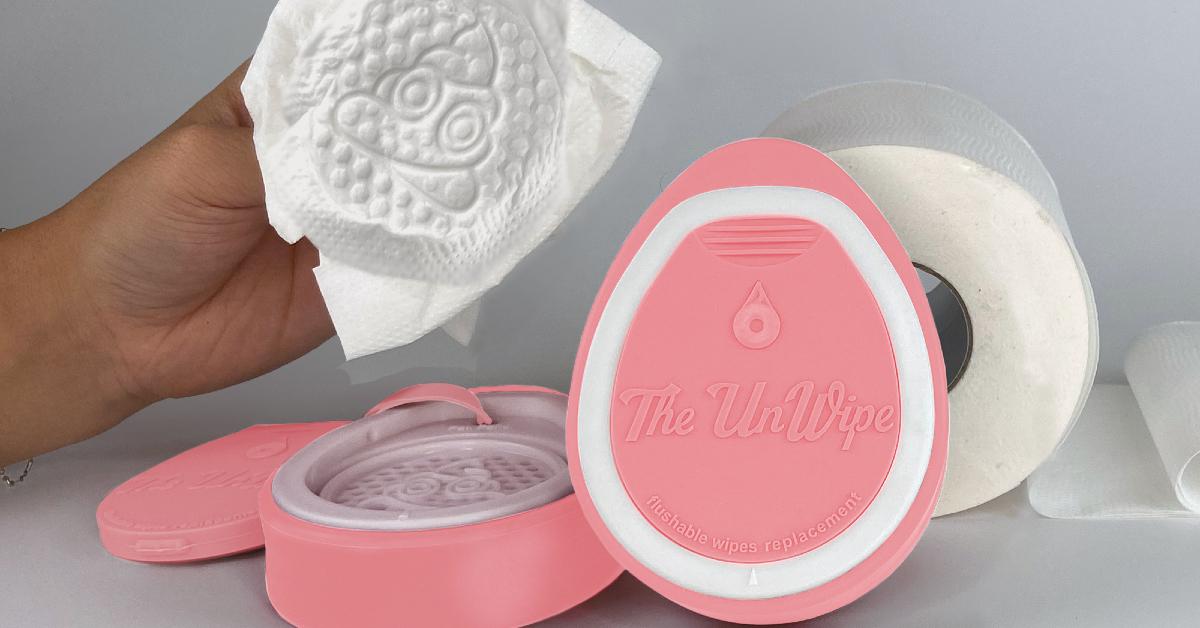 Product image of The Unwipe in pink alongside a roll of toilet paper and a hand holding a textured eco-friendly wipe