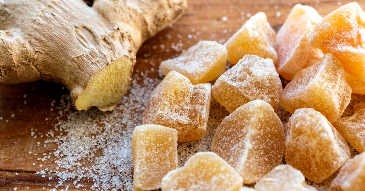 A ginger root and some ginger chews on a wooden background