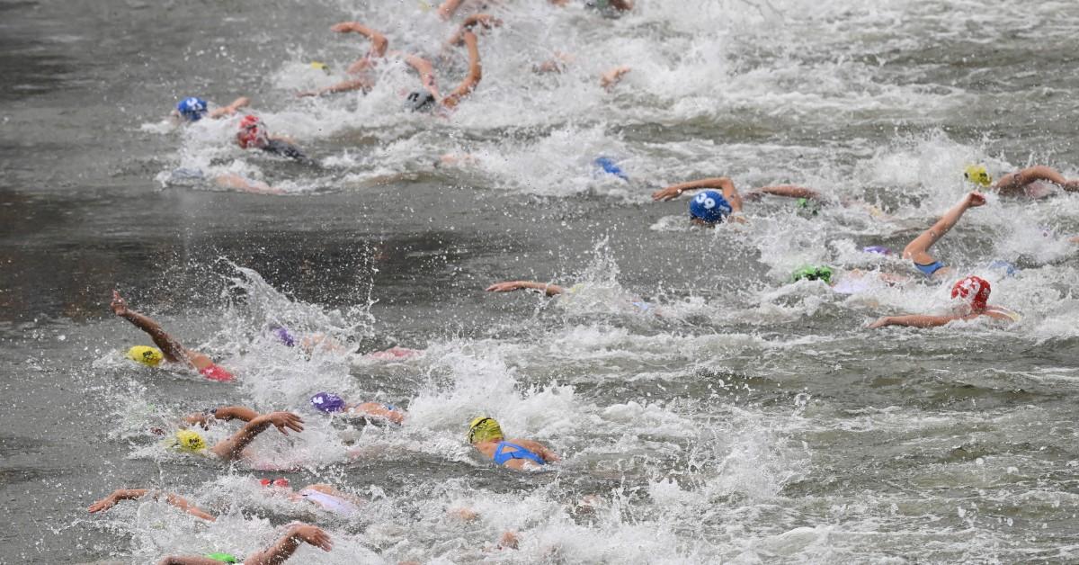 A group of women splash and swim in the Seine while competing in the Paris Olympics