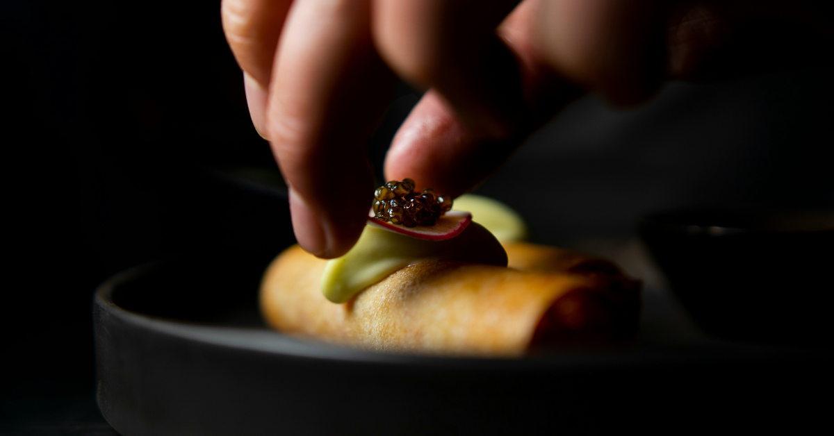 A small pile of black caviar is being added to a plated dish