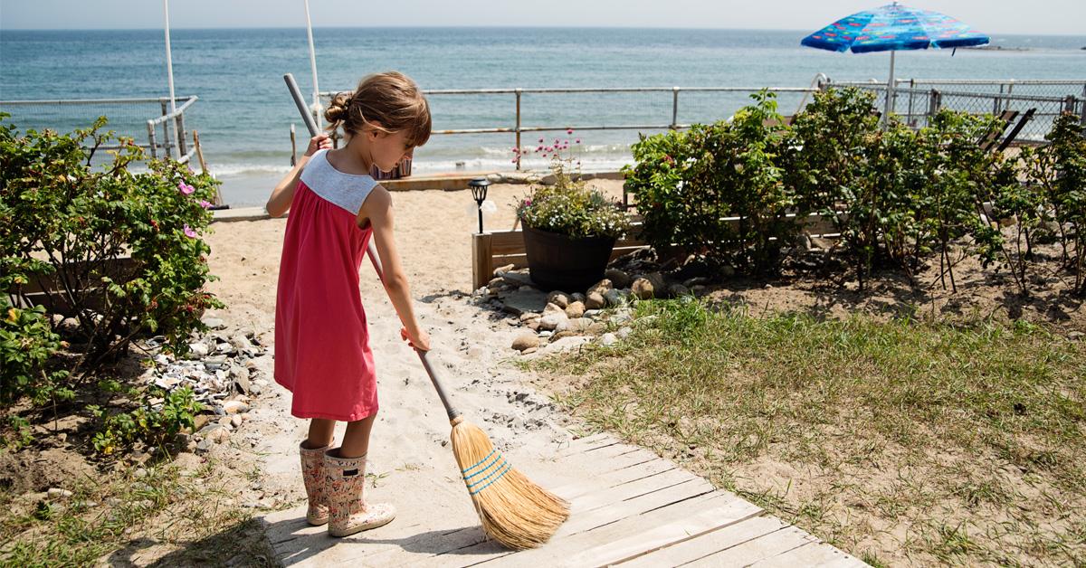 little girl sweeping the boardwalk at the beach