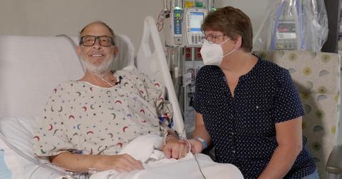 Lawrence Faucette smiles in hospital bed next to wife