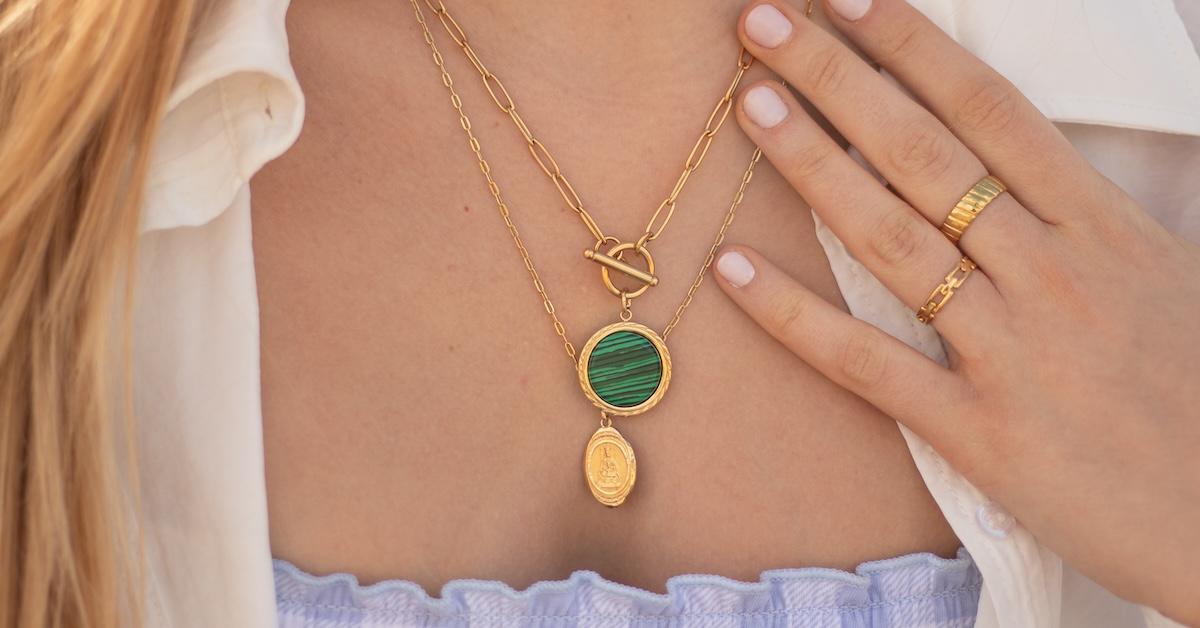 Woman wearing a gold necklace and gold rings.