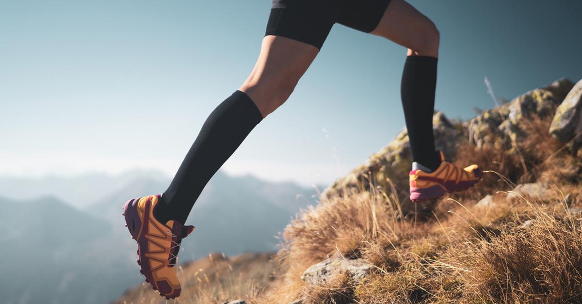 Person wearing compression socks with hiking sneakers up the side of a mountain