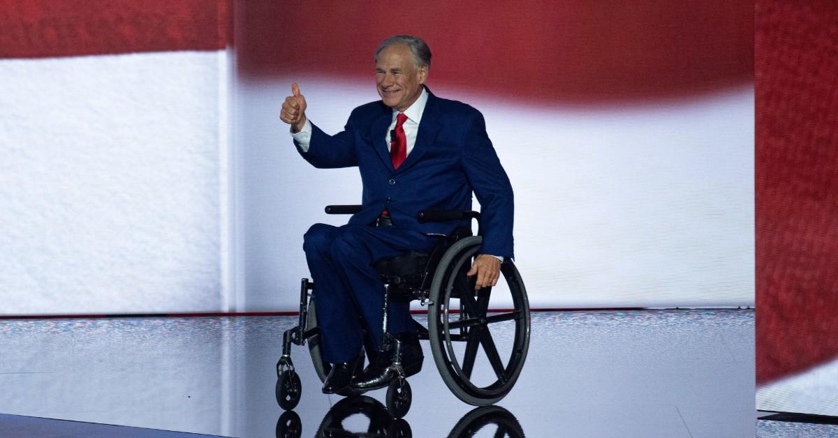 Greg Abbott gives a thumbs up while on stage in a suit
