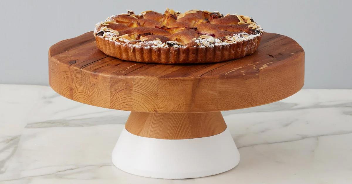 Wooden cake stand with white bottom holding a pie