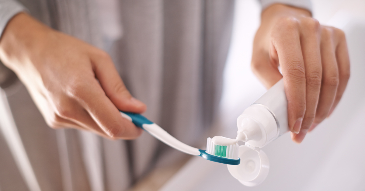 A woman puts toothpaste onto a toothbrush