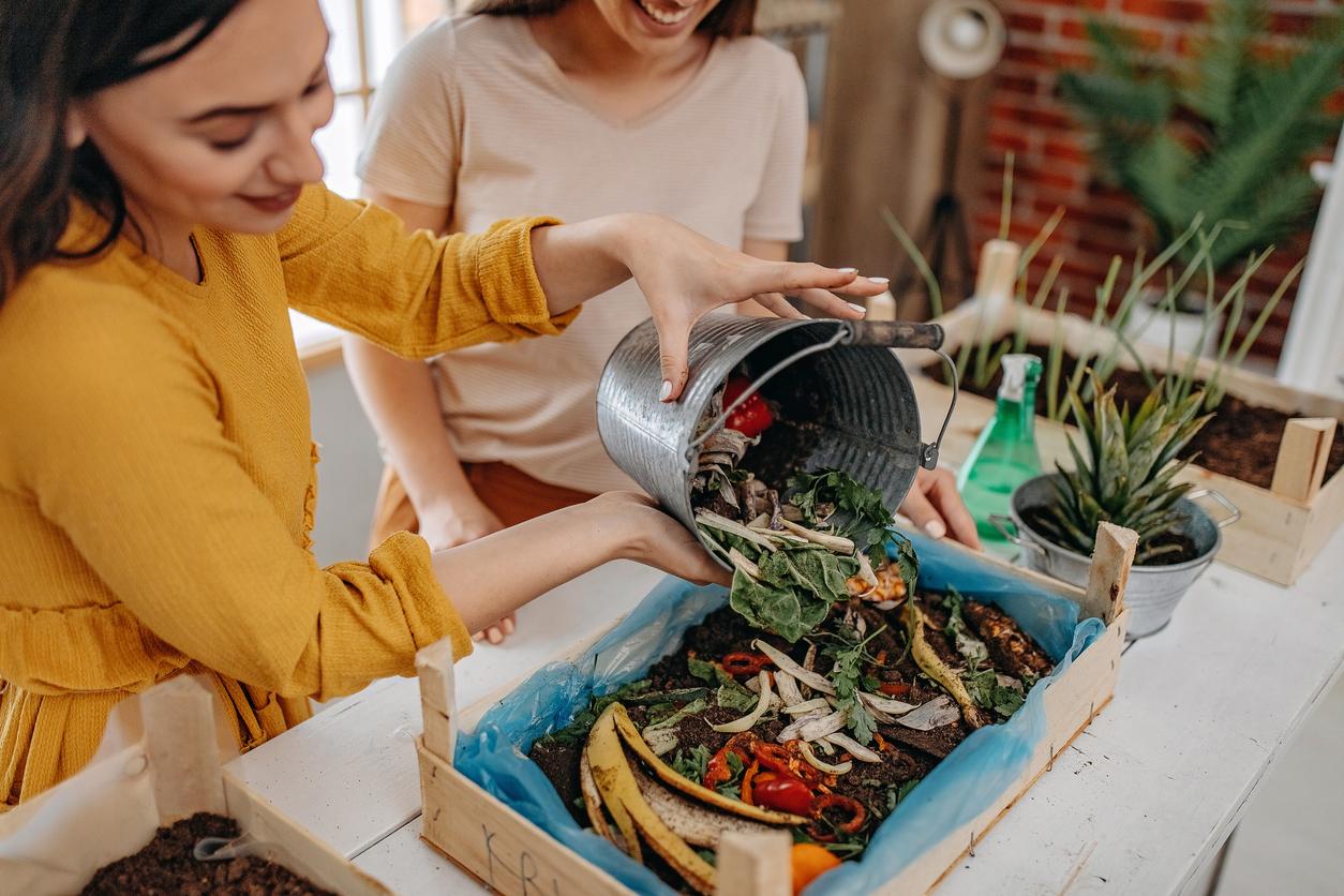 Two women prepare to compost food scraps on a patio.