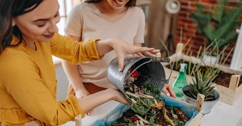 Two women prepare to compost food scraps on a patio.