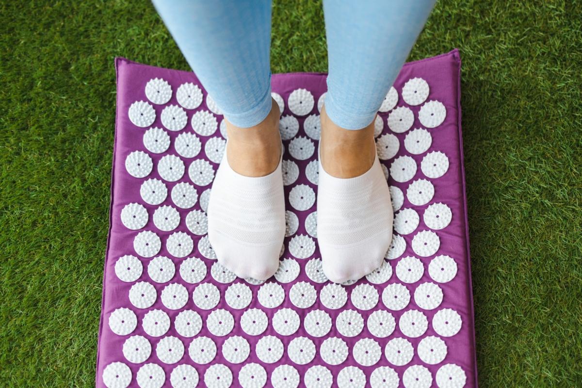 Person standing on purple acupressure mat in socks