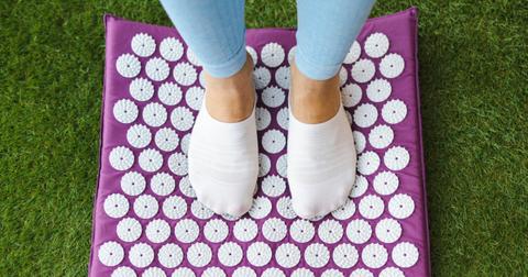 Person standing on purple acupressure mat in socks