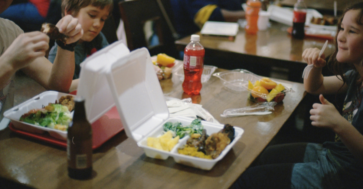 Students sit around a table eating school lunch