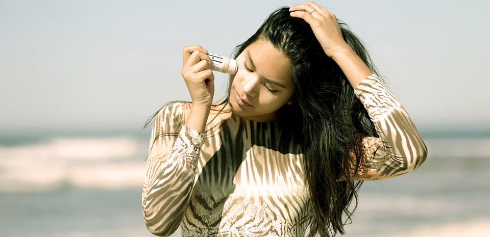 Woman putting sunscreen on her face at the beach.