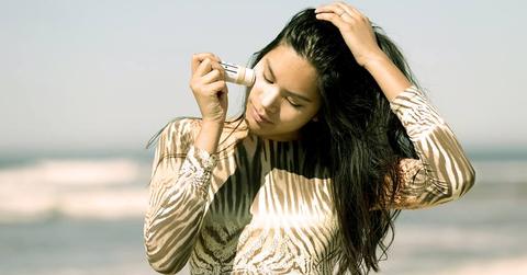 Woman putting sunscreen on her face at the beach.