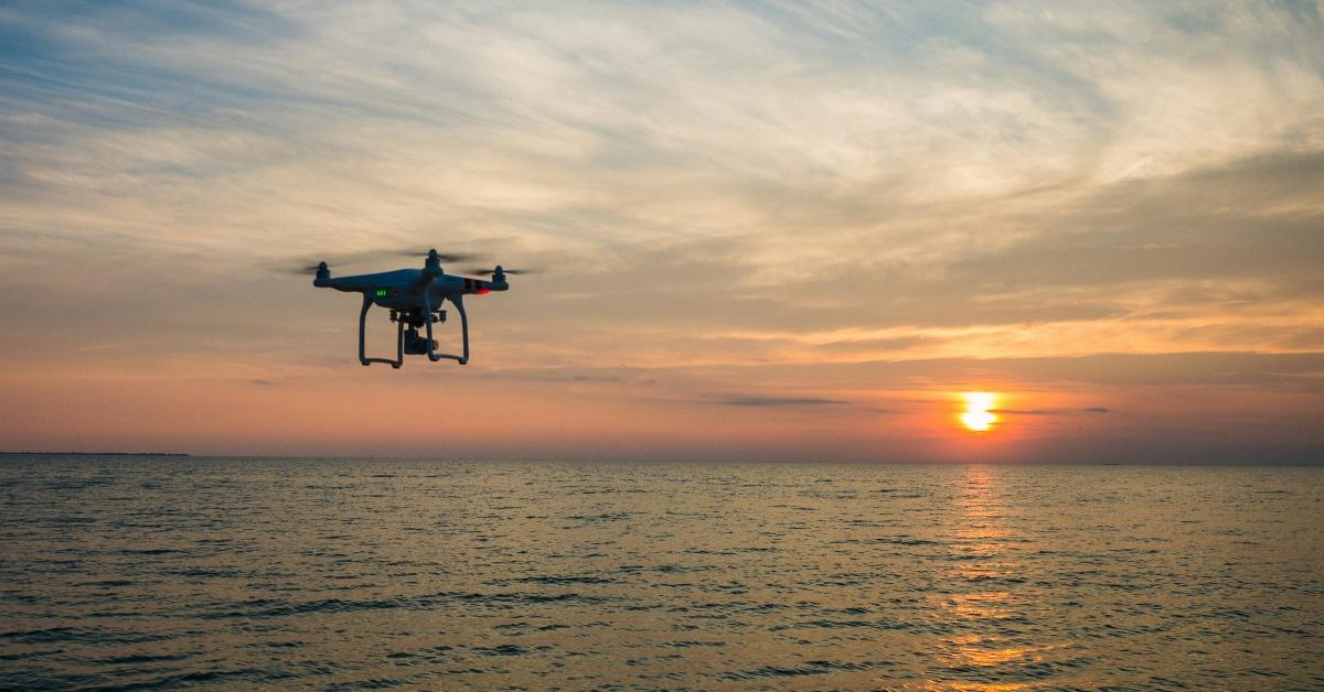 Drone flying over the ocean with the sunset in the background. 