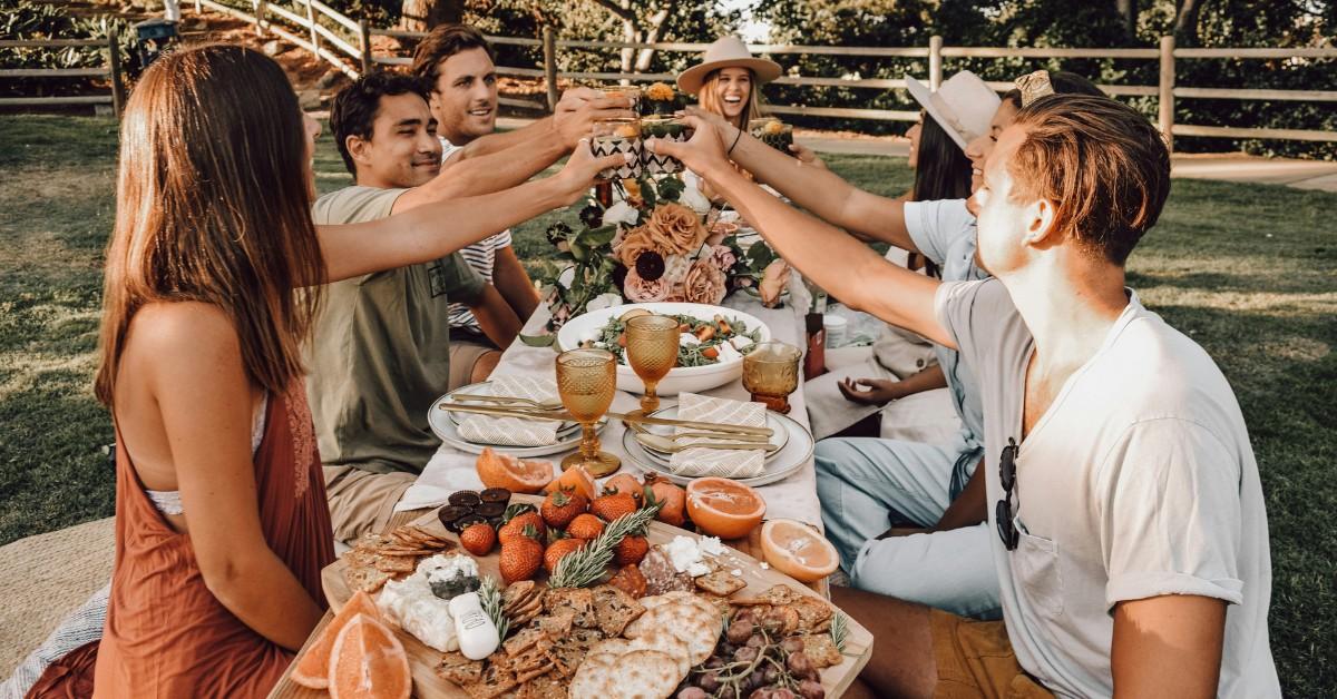 A bunch of young adults clink glasses at the table