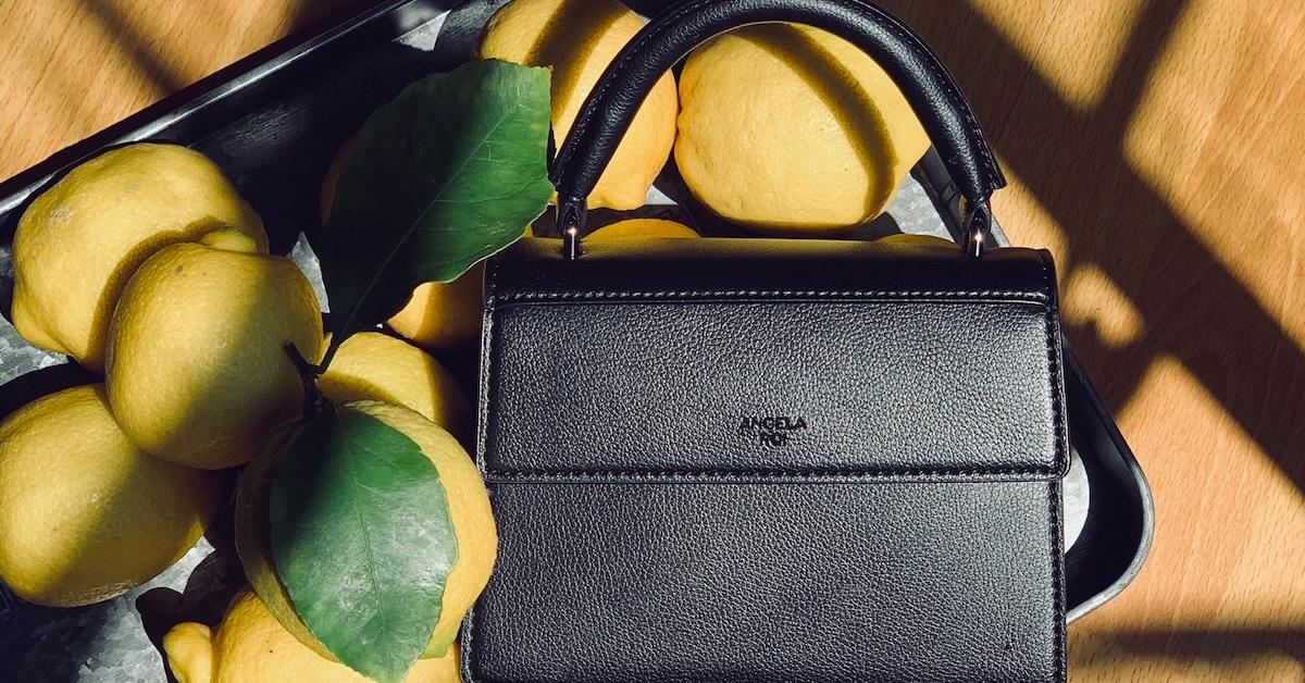 Black Angela Roi purse on a pile of lemons