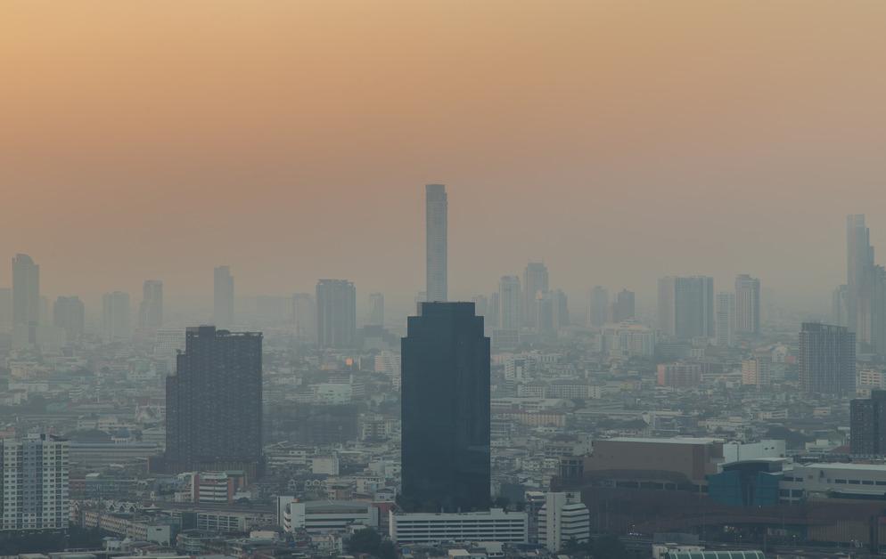 Aerial view of skyscrapers during sunset where smog covers the city. 