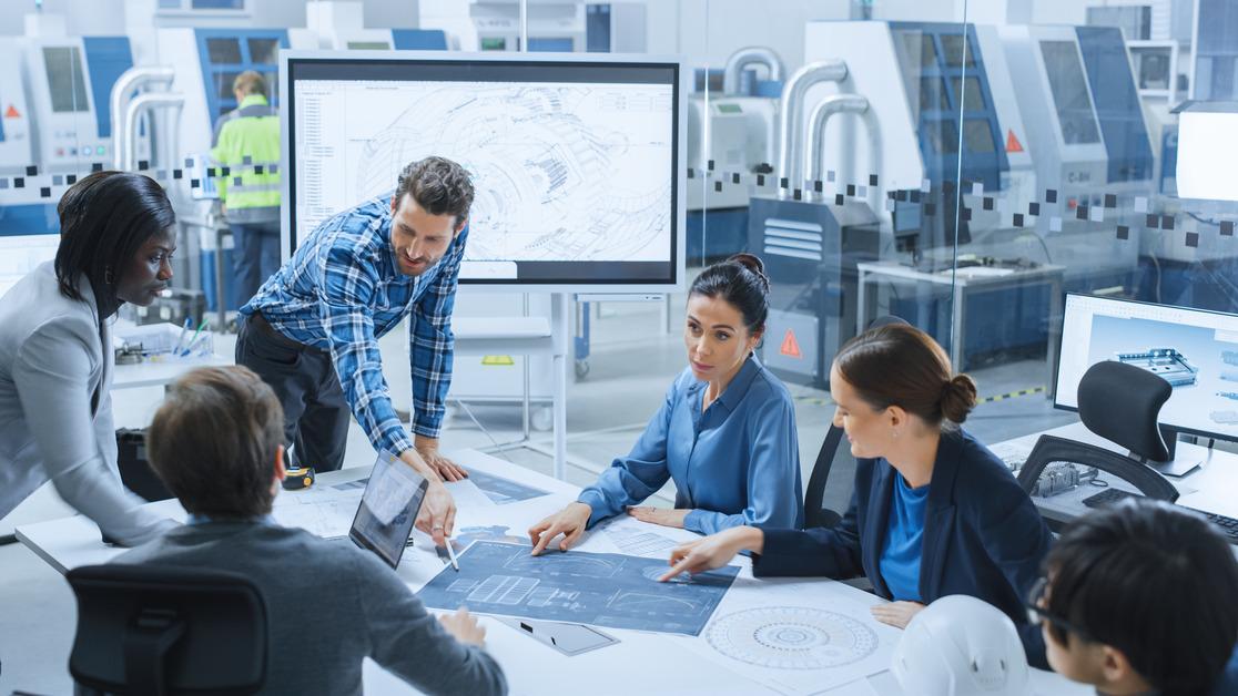 A team of engineers in a meeting room talking at a conference table. 