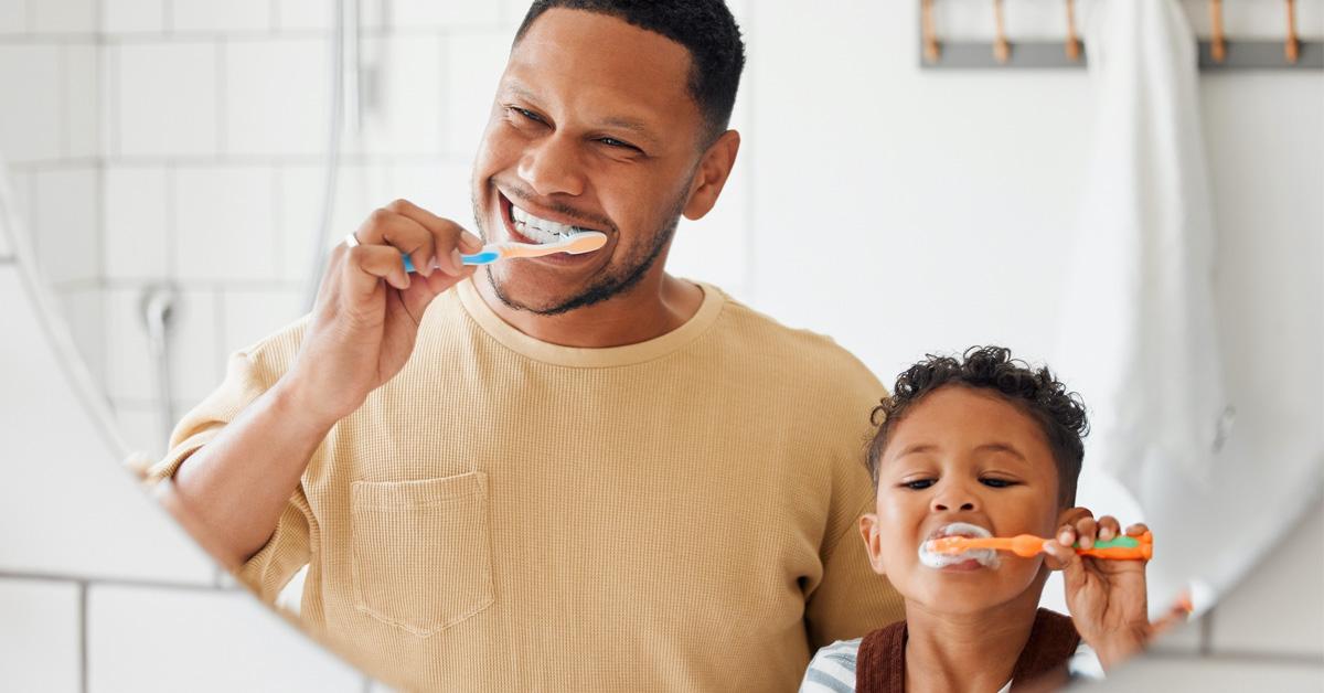 father and son brushing their teeth in the mirror