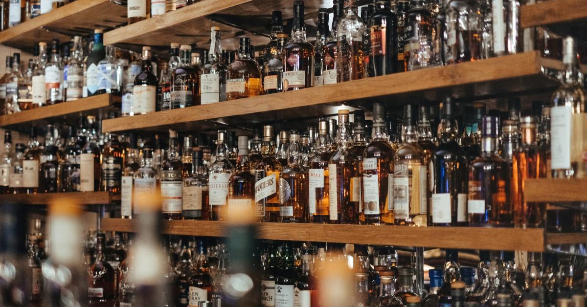 Bottles of alcohol sit on a shelf behind a bar