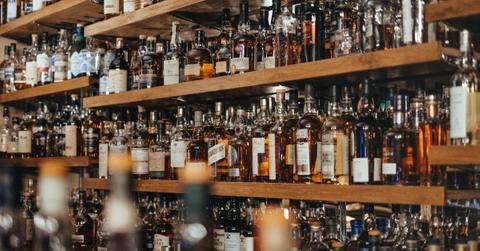 Bottles of alcohol sit on a shelf behind a bar