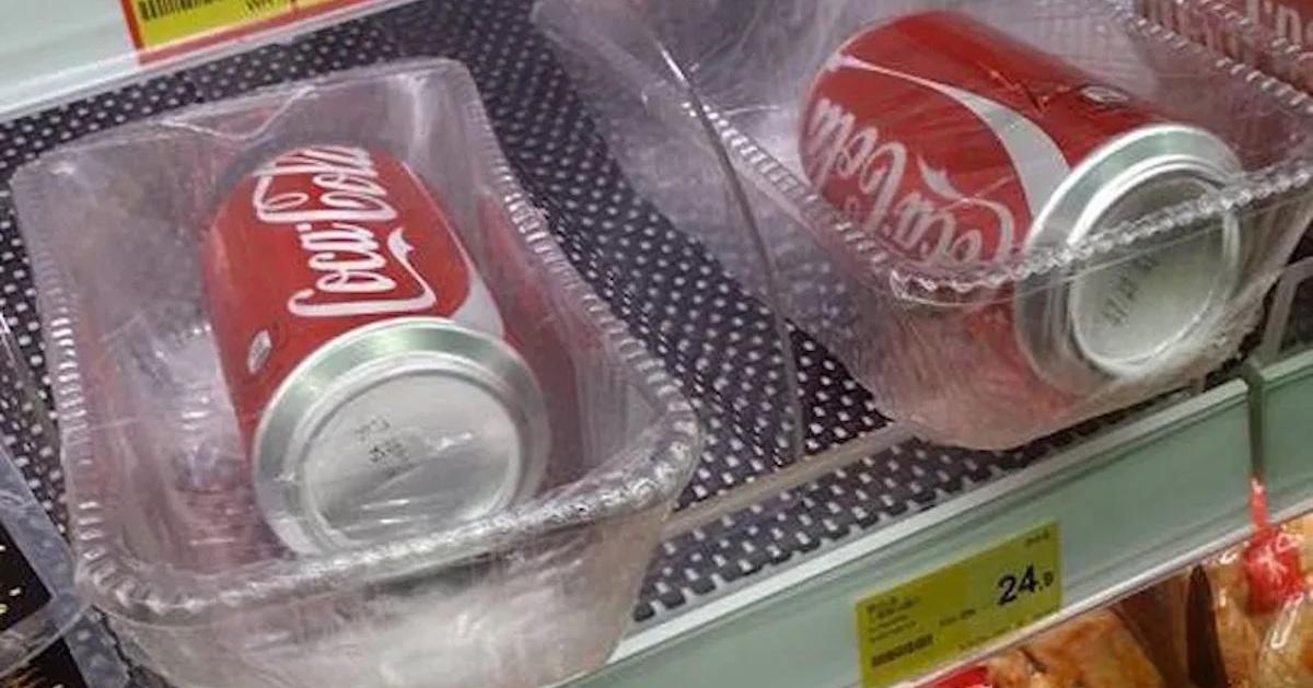 Coca-Cola cans placed in their own plastic trays and covered with plastic wrap on a store shelf