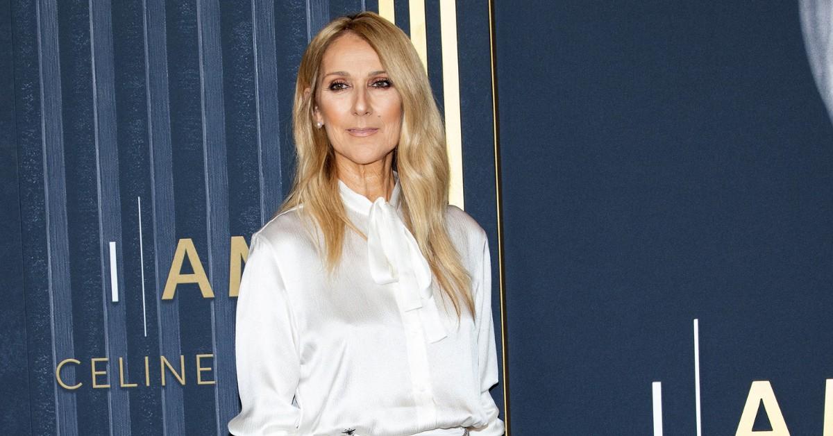 Celine Dion poses on the red carpet in front of a sign for her own show