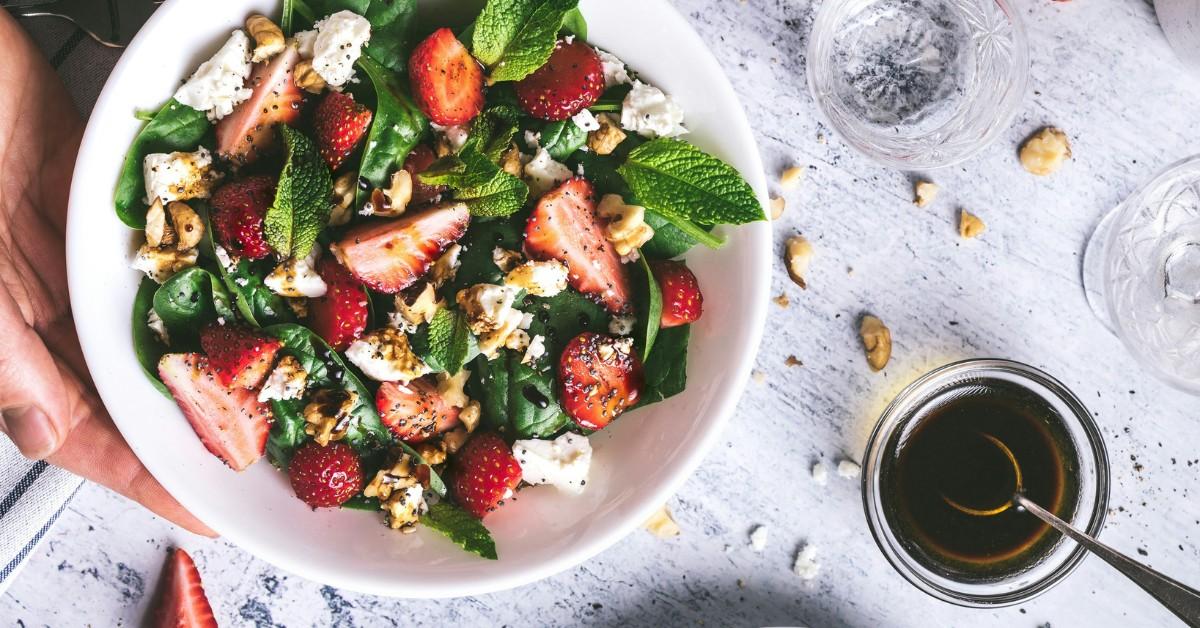A woman holds a bowl of salad
