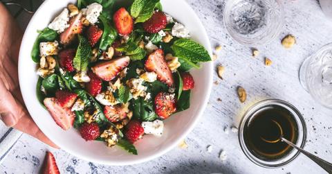 A woman holds a bowl of salad