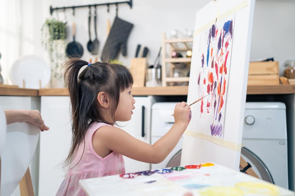 A young girl painting in a kitchen