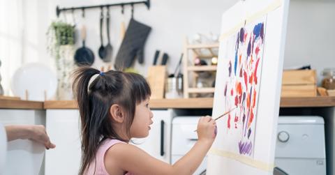 A young girl painting in a kitchen