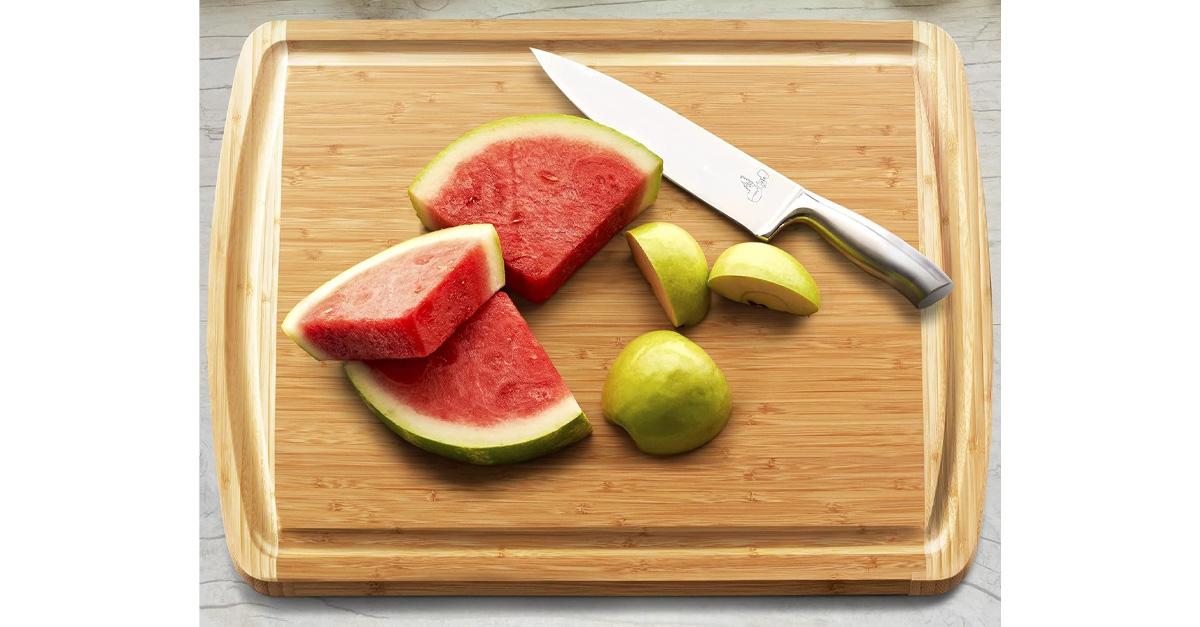 Bamboo cutting board with cut-up watermelon and a knife