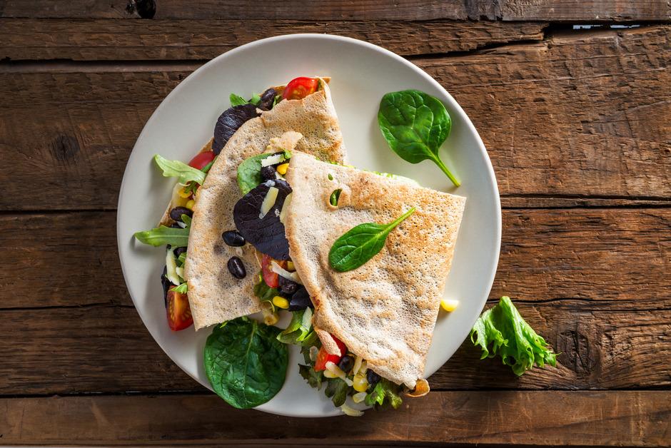 An overhead photo of a quesadilla full of vegetables on a plate. 