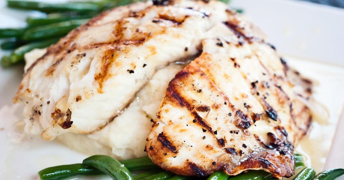 Plate of cooked tilapia with green beans and mashed potatoes.