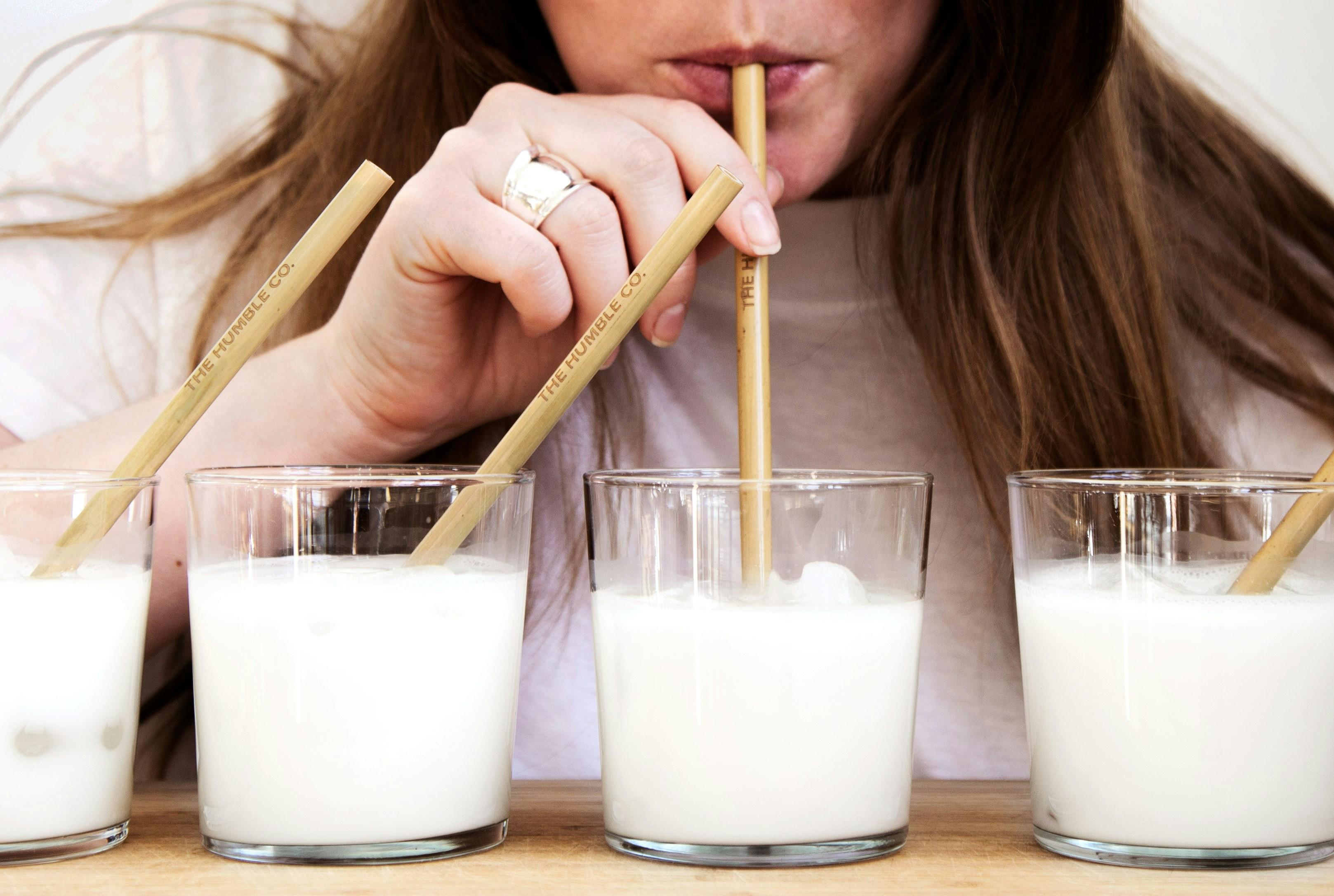 A person sips milk through four different straws.