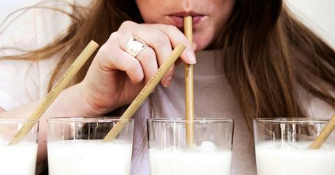 A person sips milk through four different straws.