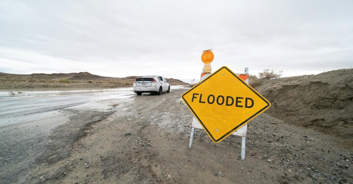 A yellow sign cautions drivers that the roadway is flooded