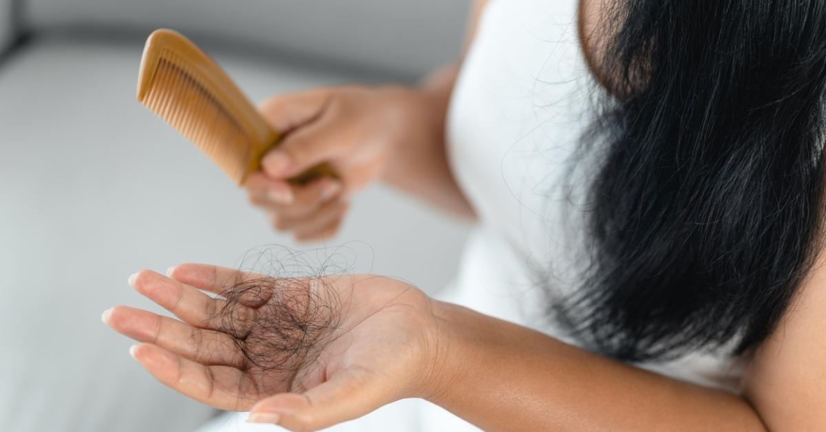 Woman combing her hair and hair falling out. 